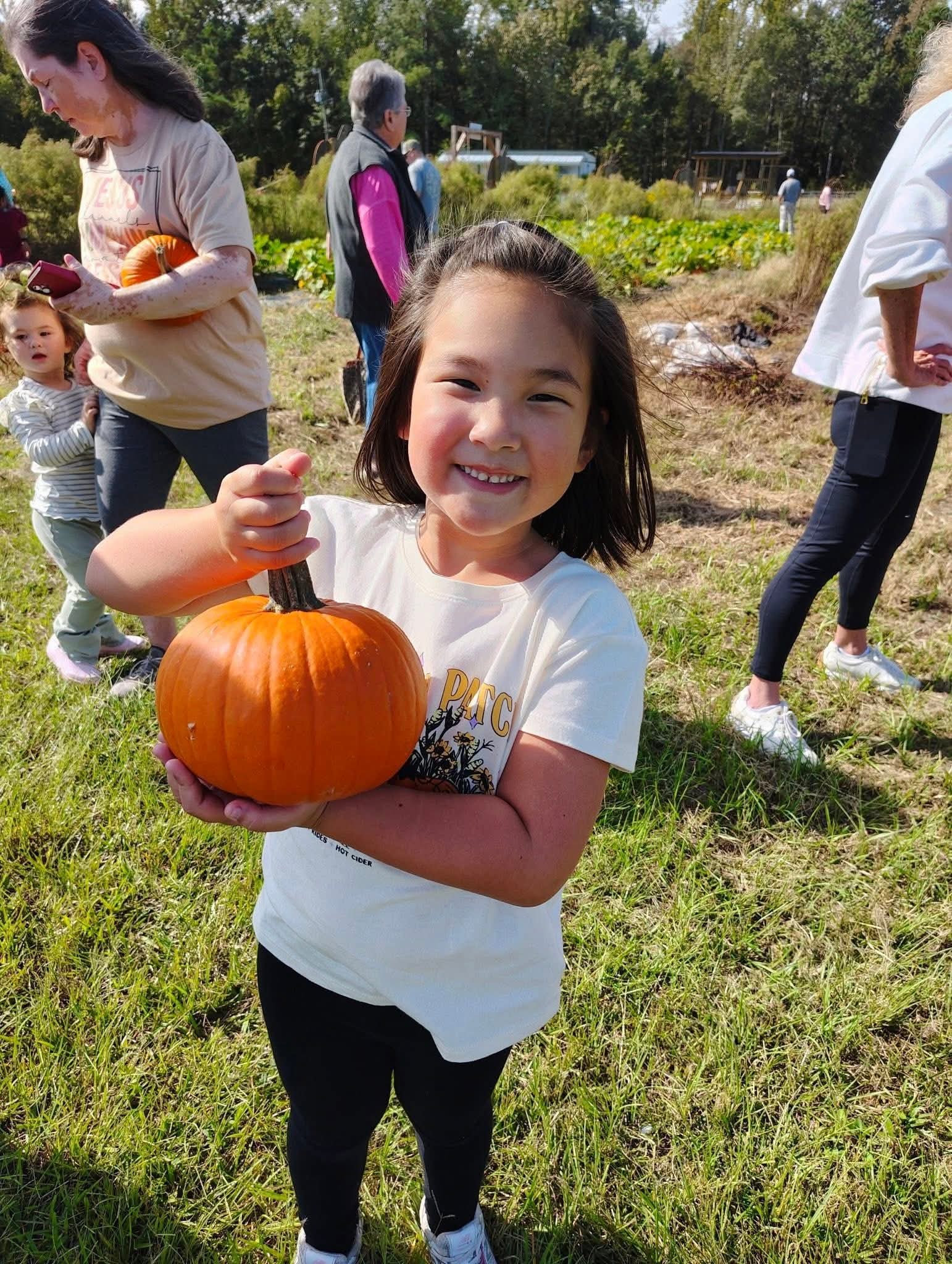 A Clarendon Hall K5 student holding a pumpkin during a fall field trip.