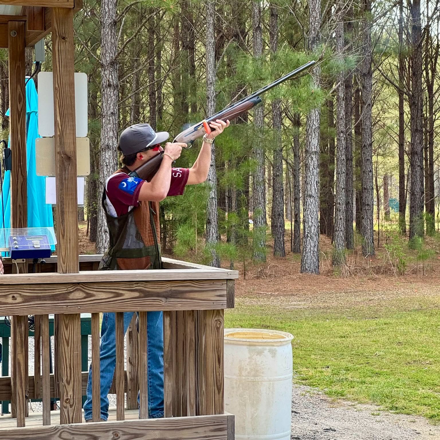 Saints Sporting Clays athlete aiming toward a clay target at an outdoor station